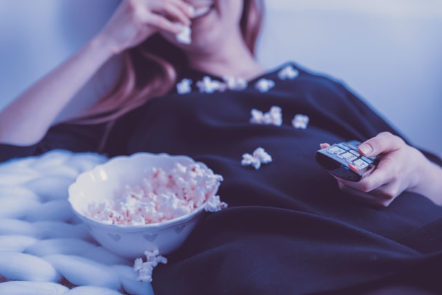 a person eating popcorn and watching television