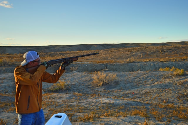 a person aiming their rifle in an open ground